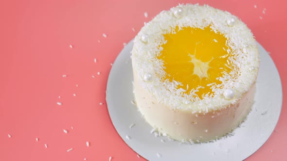 Cake with Orange and Coconut Shavings Spun on a Pink Background