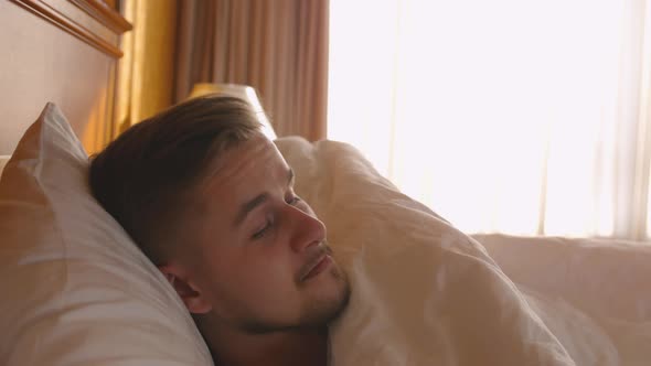 Handsome Man Waking Up and Opening the Window Curtain on a Sunny Morning in a Hotel Room a Man