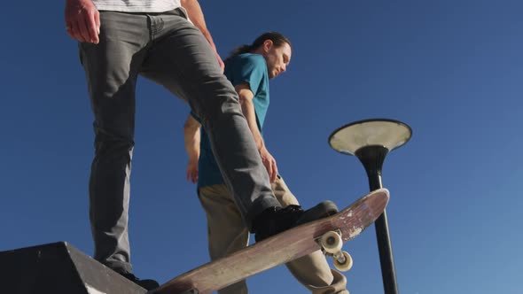 Low section of two male friends skateboarding on sunny day