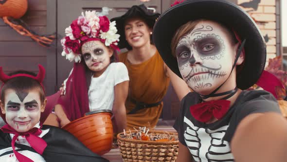 Boy Taking Selfie with Woman and Kids in Halloween Costumes