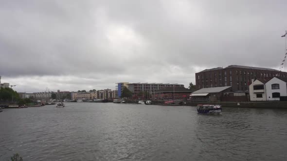 Bristol harbourside with boats travelling down the river Avon on an overcast cloudy summers day