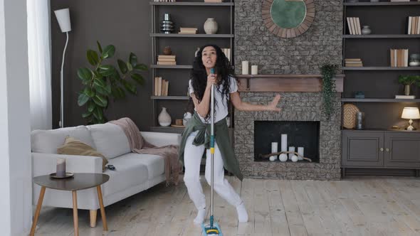 Happy Young Funny Woman Cleans in Modern Living Room Singing Song Using Mop As Microphone Active