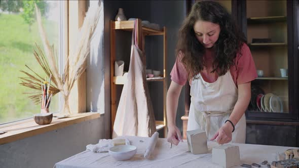 Making Pottery in Workshop Woman is Working with Piece of Clay