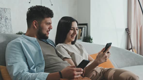 Laughing Couple Watching Online Content On Smartphones