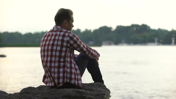Depressed Adult Male Sitting on Riverside and Thinking About Divorce, Loneliness