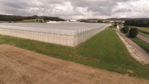 Aerial view of an greenhouse near a field with blu sky on a sunny day. Super Wide shot.