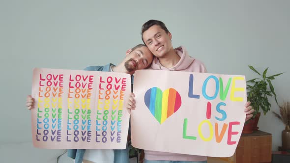 Two Young Handsome Guys are Showing Lgbt Posters Looking at Each Other and Smiling