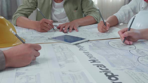 Close Up Of Group Of Asian Engineers Drawing Building Construction At The Office