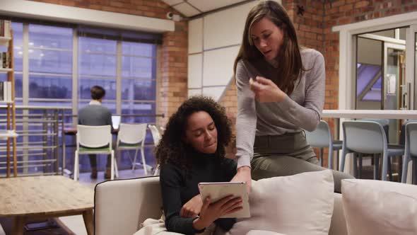 Two creative bussinesswoman discussing over digital table in modern office