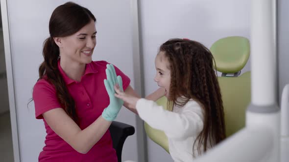 Happy Female Dentist Plays with Child  Claps Hands Before Examination Teeth