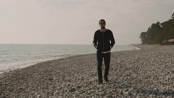 a Lonely Man Strolls Along a Stony Beach, Waves Are Beating Against the Shore