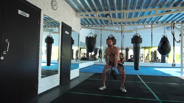 An Athlete Exercises with Kettlebells