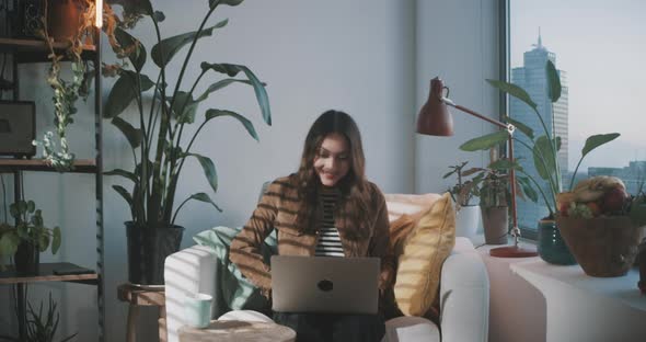 Woman smiles while working on laptop