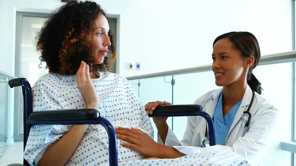 Doctor interacting with pregnant woman in corridor