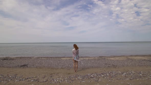 Hippie Female Traveler Standing By the Sea Alone Relaxing in Nature Wearing Stripy Blanket