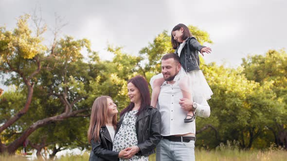 Young Parents with Two Kids Posing Among High Grass at Green Garden