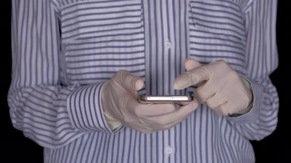 Female Hand in Sterile Medical Gloves Holding Smartphone on Black Background