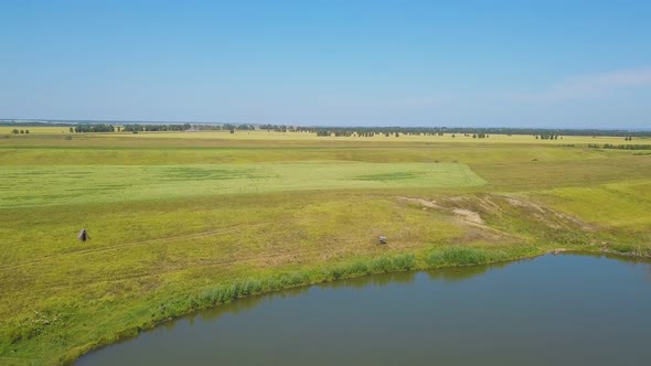 Tranquil Lake and Field Under Boundless Sky Aerial Panorama