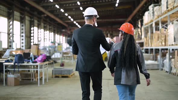 A young manager and a warehouse worker walk through the production workshop