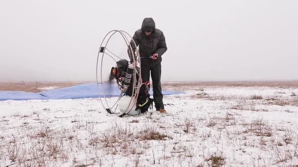 Man Starts To Work a Propeller Motor Engine of the Paramotor Paraglider