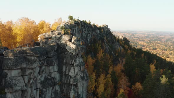 Aerial View of a Cliff Surrounded By a Colorful Autumn Forest at Sunset