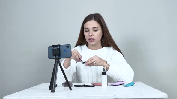 Background Caucasian Girl Blogger Sits at Table. Shows a Box of Blush, Tells.