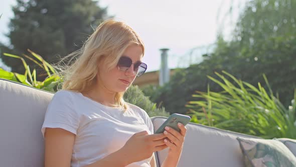 Young Woman Enjoys Talking on the Phone Texting with Someone in a Wonderful Place Sitting in a White