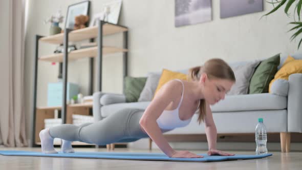 Young Woman Doing Pushups on Yoga Mat at Home