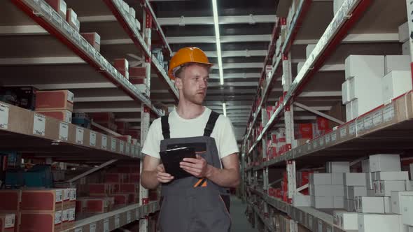 Worker in Helmet Is Checking Materials at the Factory