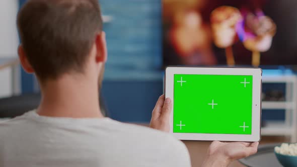 Closeup of Man Holding Digital Tablet with Green Screen Watching Online Video Content Sitting on