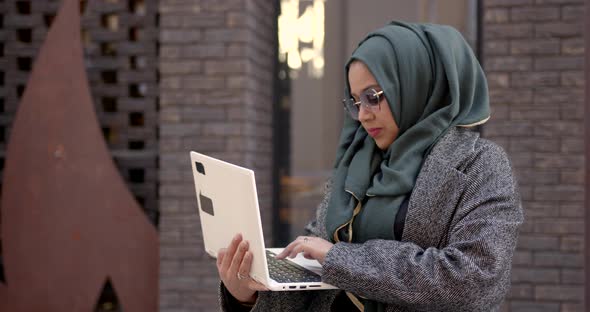 Muslim Woman Using Laptop Standing Outside