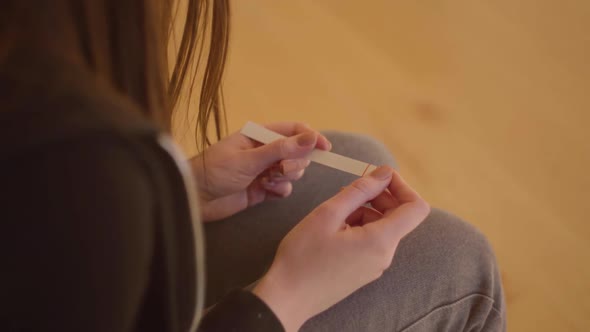 Young Sad Nervous Woman Holding a Pregnancy Test with Two Stripes