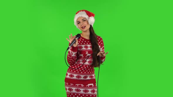 Sweety Girl in Santa Claus Hat Is Singing Into a Microphone and Moving To the Beat of Music. Green