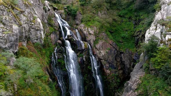 Aerial View Of Fervenza do Toxa Waterfalls Cascading Down Rockface. Pedestal Up, Tilt down Shot