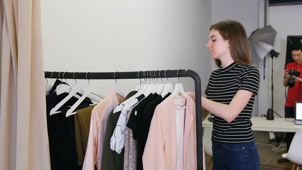 Female stylish selecting apparel from clothes rack