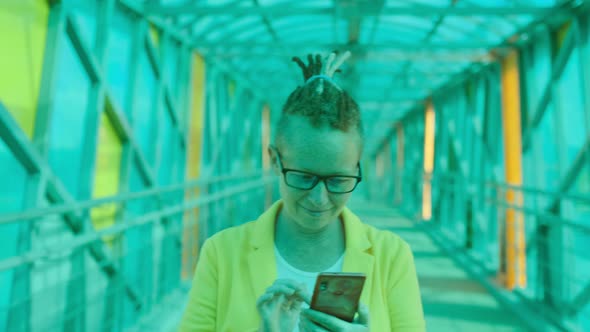 Stylish adult woman with phone walking along long passage or corridor