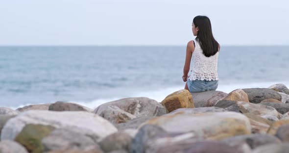 Woman sitting at beach and looking far away