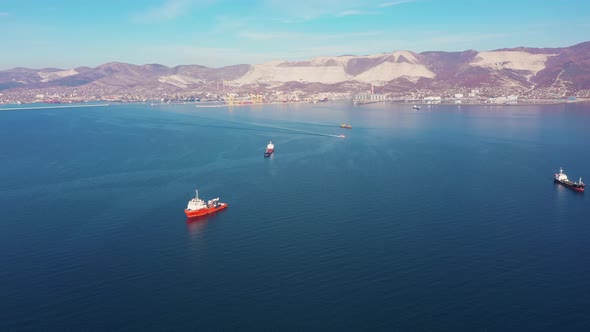 Aerial View, Vessels Drift on Calm Blue Ocean Surface Against Hilly Coast