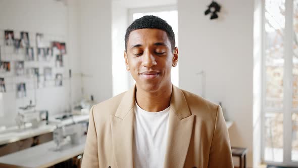 Portrait of Young Positive African American Guy Wearing Suit Smiling to Camera at Workshop