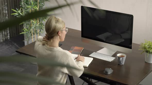 Woman Looking at Monitor's Computer Listening Conference Lesson Writing and Taking Notes