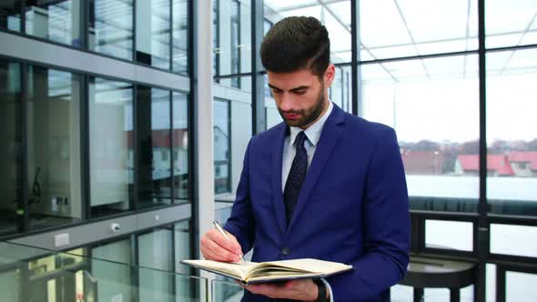 Businessman writing in diary at office