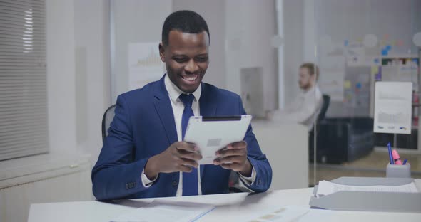 Smiling African Office Manager Using Tablet Computer