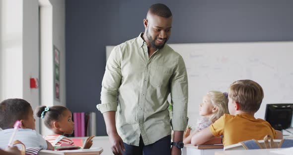 Video of happy african american male teacher during lesson with class of diverse pupils alt