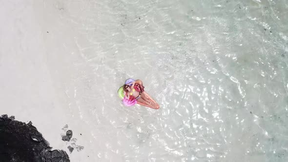 Aerial view of people in summer holiday vacation with beautiful girl on coloured trendy lilo