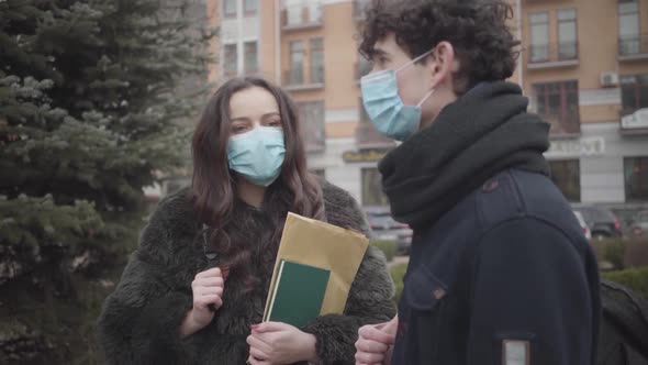 Portrait of Young Cute Caucasian Girl in Face Mask Discussing Coronavirus News with Groupmate