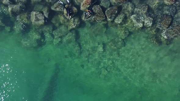 Unique rotating view of two people snorkeling in deep water next to a man-made structure formed with