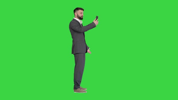 Handsome Young Businessman Making a Video Call with His Smartphone on a Green Screen, Chroma Key.