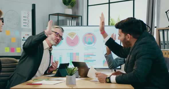 Company Giving High Five to Joyful Successful Diverse Subordinates During Meeting