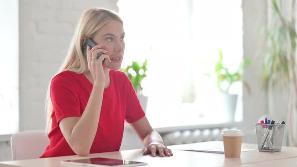 Angry Young Blonde Woman Talking on Phone at Work