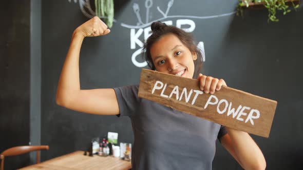 Vegan Girl Holding Wooden Sign Plant Power and Showing Strong Biceps. Healthy Lifestyle Propaganda